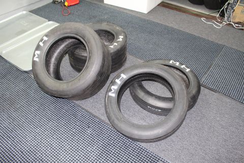 2003 Ford Crown Victoria - Four M&H bias-ply drag slicks with white sidewall lettering laid out on a gray carpet.