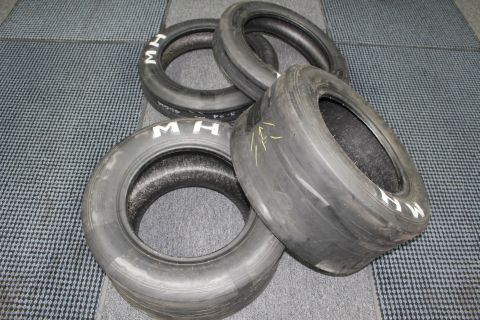 2003 Ford Crown Victoria - Four worn M&H drag slicks with white M H markings stacked on a gray floor.