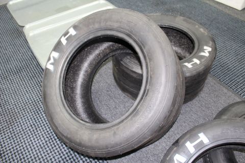 2003 Ford Crown Victoria - M&H Racemaster drag slicks with white sidewall lettering arranged on gray carpet.
