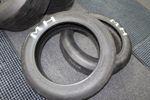 2003 Ford Crown Victoria - Two nested M&H Racemaster drag slicks with white M H lettering on a gray floor.