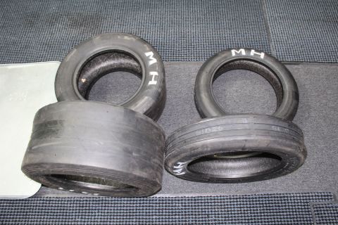 2003 Ford Crown Victoria - Several M&H drag slicks of differing widths arranged on a gray carpeted surface.