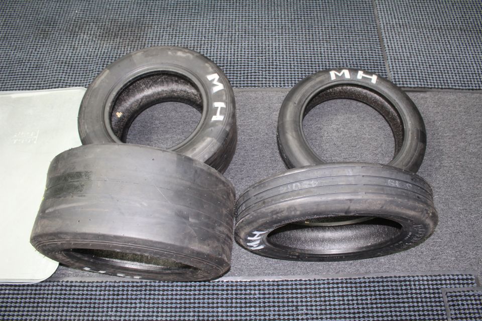 Group of M H drag slicks and a wide smooth slick on gray carpet
