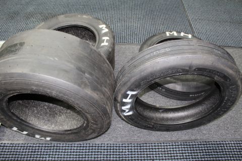 2003 Ford Crown Victoria - Wide M&H drag slicks with white sidewall lettering lined up on a gray floor.