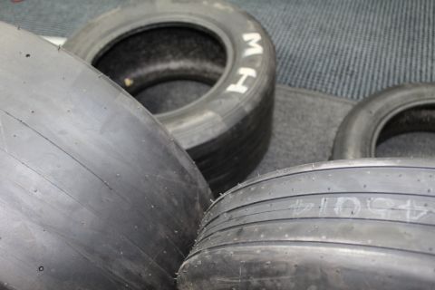 2003 Ford Crown Victoria - Close view of a wide smooth drag slick next to an M&H-lettered tire on gray carpet.