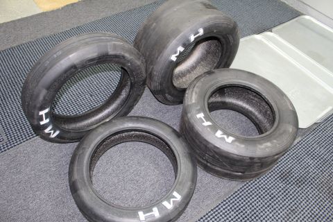 2003 Ford Crown Victoria - Four M&H drag slicks with white M H sidewall lettering laid out on a gray carpet.
