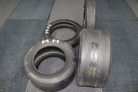 2003 Ford Crown Victoria - cluster of worn drag slicks including one tipped on its side with yellow painted arrow marks on the tread.