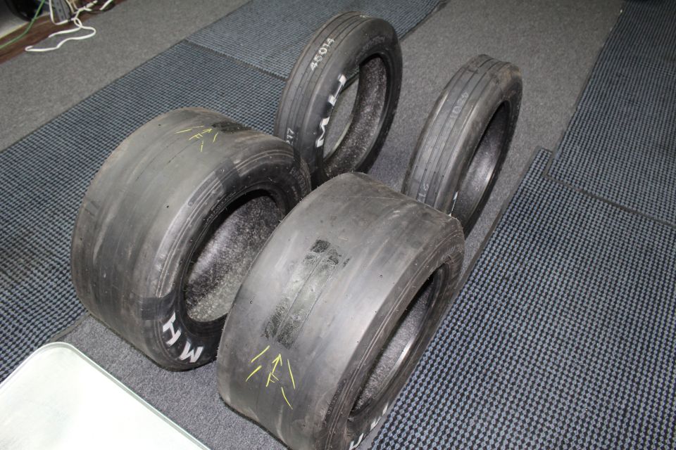 Wide and narrow drag tires with yellow arrows on dark gray floor
