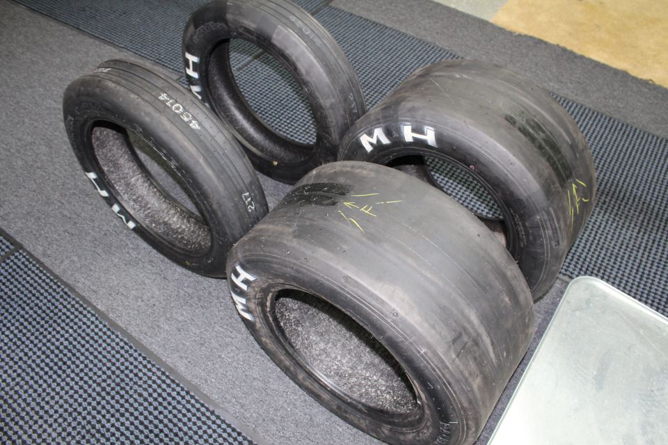 Four drag slicks with M H lettering and yellow marks on gray floor
