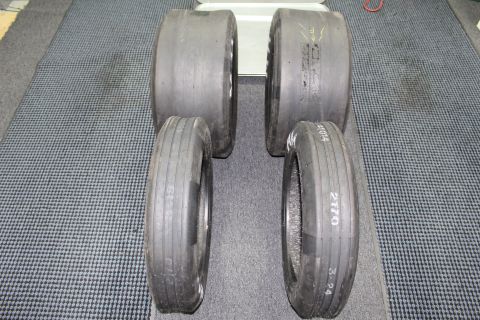 2003 Ford Crown Victoria - Four drag racing tires stood upright in two rows on a gray floor, one sidewall handwritten "2170".