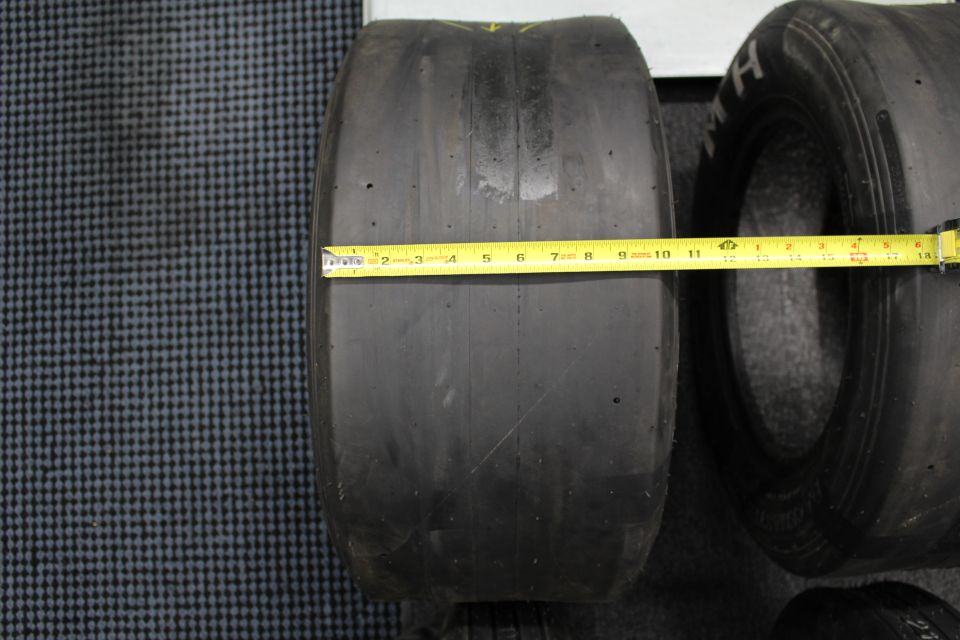 Wide drag slick measured with a yellow tape measure on gray floor