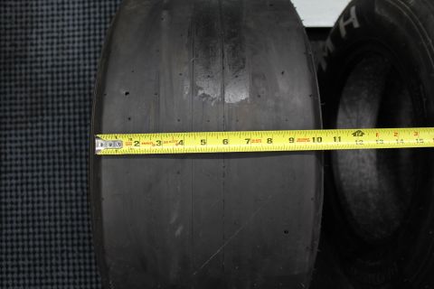 2003 Ford Crown Victoria - Close view of a drag racing slick with a yellow tape measure spanning roughly eleven inches across its tread.