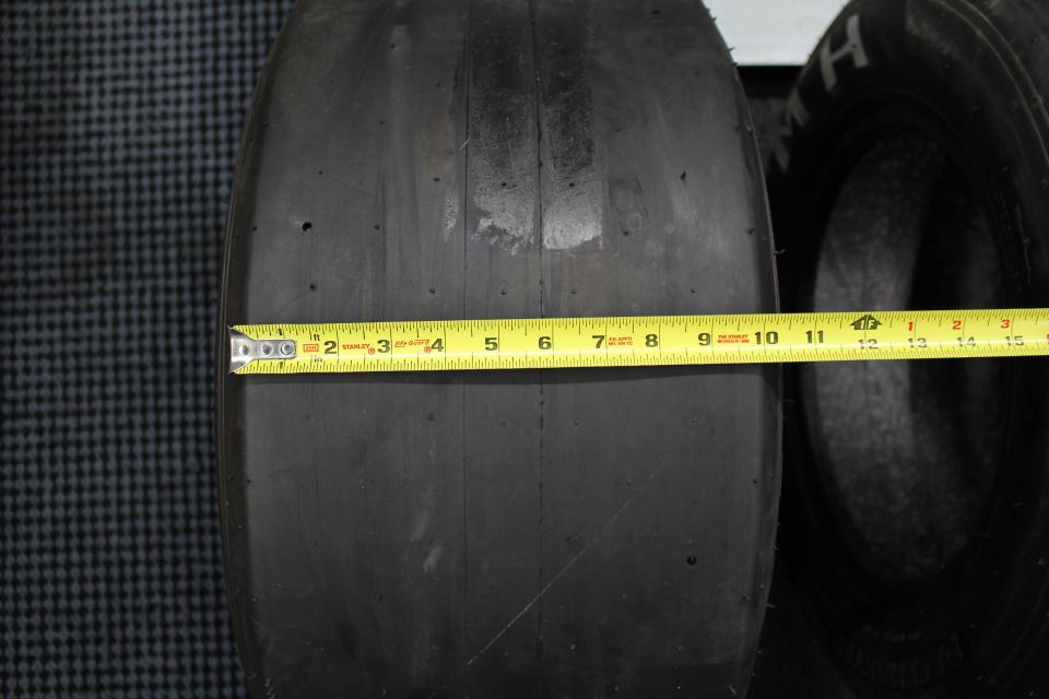 Drag slick tread width measured with yellow Stanley tape measure