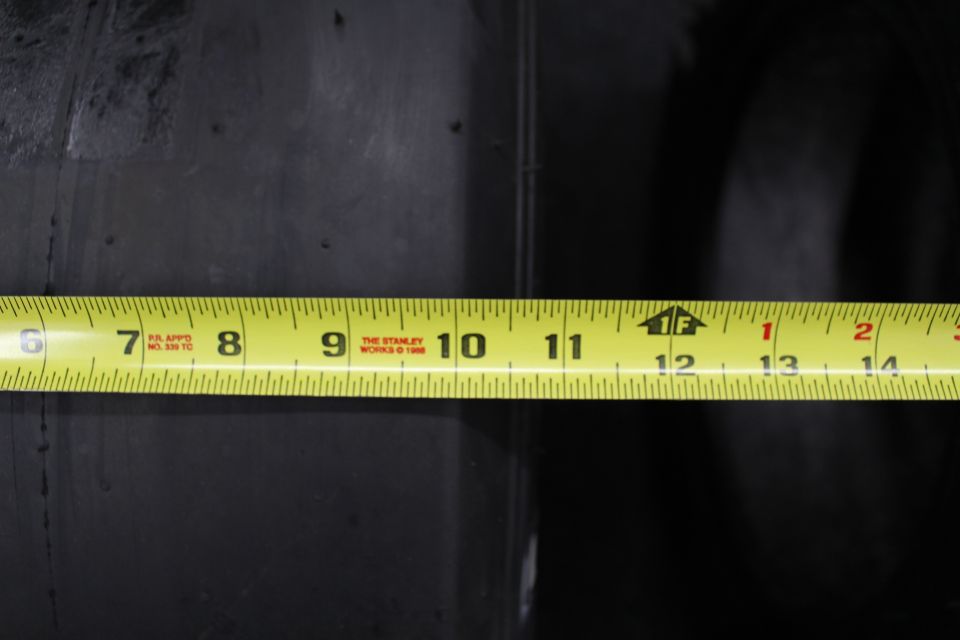 Close-up of yellow Stanley tape measure across a black tire tread