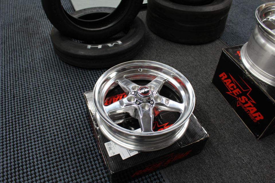 Polished five-spoke Race Star wheel sitting on its box on a garage mat