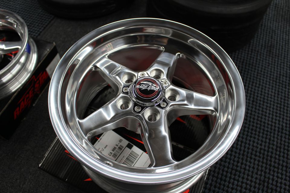 Polished Race Star five-spoke wheel face-up on box with another behind