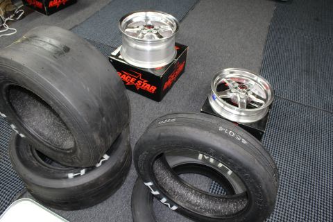 2003 Ford Crown Victoria - Wide M/H drag slick tires lie beside two polished Race Star five-spoke wheels on boxes in a garage.