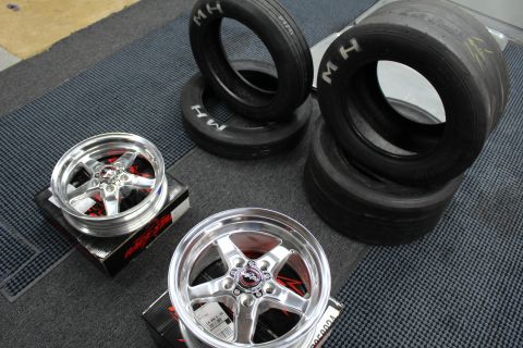2003 Ford Crown Victoria - Two polished Race Star five-spoke wheels sit on boxes near a stack of M/H drag tires in a garage.