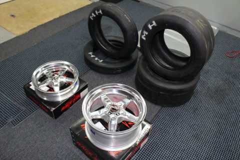 2003 Ford Crown Victoria - Two polished Race Star five-spoke wheels rest on boxes beside stacked M/H drag tires on a garage mat.