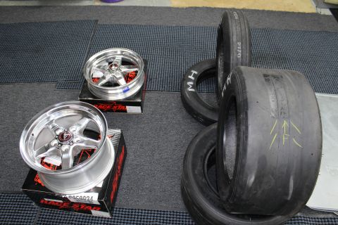 2003 Ford Crown Victoria - Two polished Race Star five-spoke wheels sit on boxes next to wide M/H drag slick tires in a garage.