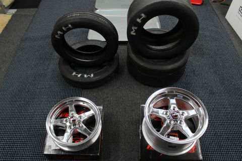 2003 Ford Crown Victoria - M/H drag tires sit above two polished Race Star five-spoke wheels resting on boxes on a garage mat.