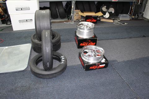 2003 Ford Crown Victoria - M/H drag slicks and polished Race Star wheels on boxes sit before Kenne Bell supercharger boxes in a garage.