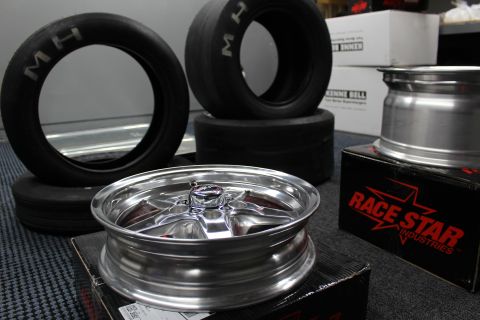 2003 Ford Crown Victoria - polished aluminum drag wheel sits on a box beside stacked M/H drag tires and a Race Star Industries carton.