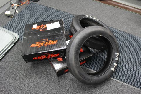 2003 Ford Crown Victoria - M/H drag slick tires sit stacked next to black Race Star Industries boxes with orange lettering on a floor mat.