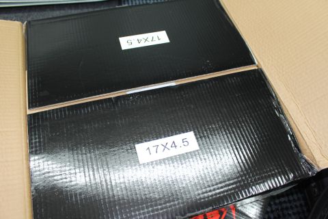 2003 Ford Crown Victoria - Two black wheel boxes labeled 17X4.5 in white sit stacked on a cardboard surface.
