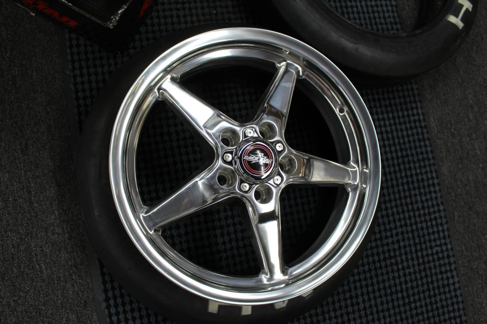 Polished 5-spoke drag wheel face-up on a tire and floor mat