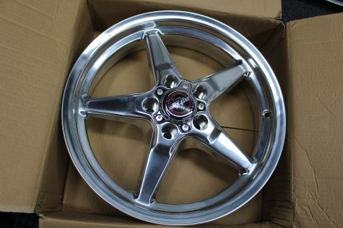 2003 Ford Crown Victoria - Overhead view of a polished five-spoke drag-racing wheel with a red center cap sitting inside a cardboard box.