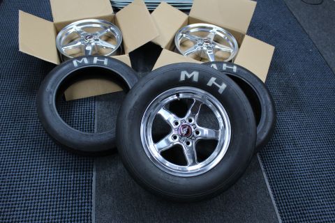 2003 Ford Crown Victoria - polished five-spoke wheel mounted on an MH slick stands between two boxed bare wheels on a dark mat.