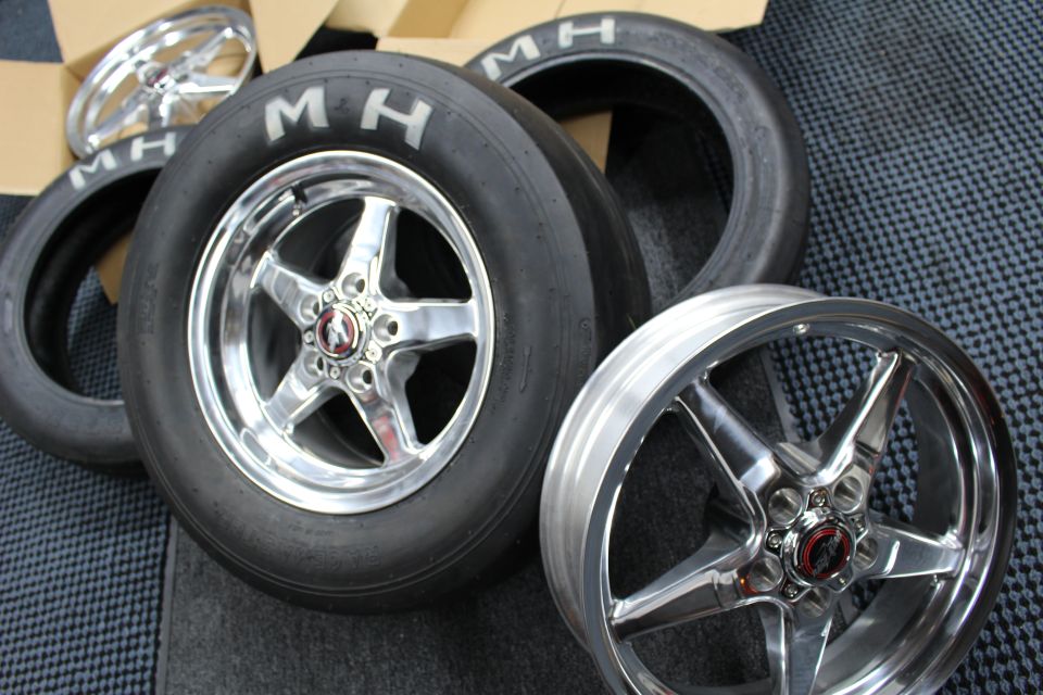 Two polished wheels mounted on MH slicks leaning together on a checkered mat