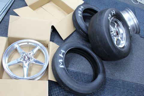 2003 Ford Crown Victoria - bare polished wheel in a box sits beside a mounted MH slick and a loose skinny MH tire.