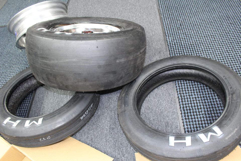 Wide drag slick mounted on a polished wheel with two skinny MH tires