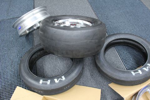 2003 Ford Crown Victoria - wide drag slick mounted on a polished wheel is stacked over two skinny MH tires and a bare wheel.
