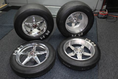 2003 Ford Crown Victoria - Four MH drag slicks mounted on polished five-spoke wheels stand together on a mat in a garage.