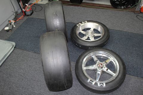 2003 Ford Crown Victoria - Two stacked wide drag slicks sit beside two MH drag tires mounted on polished and machined wheels.