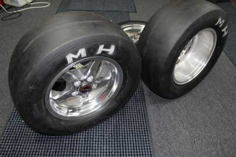 2003 Ford Crown Victoria - pair of M&H Racemaster drag slicks mounted on polished five-spoke aluminum wheels resting on a gray checkered shop floor.