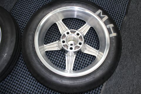 2003 Ford Crown Victoria - Close-up of a brushed-finish five-spoke aluminum drag wheel mounted in a slick tire resting on a checkered floor.