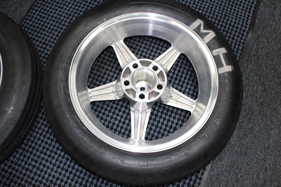 Close-up of a brushed five-spoke aluminum drag wheel mounted in a slick tire