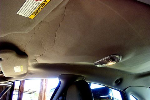 2000 Ford Taurus - The headliner in this vehicle is peeling and cracking, indicating wear and potential need for repair.