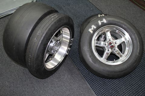 2003 Ford Crown Victoria - Two drag slick tires on polished aluminum wheels, including an M&H slick on a polished five-spoke wheel, on a checkered floor.