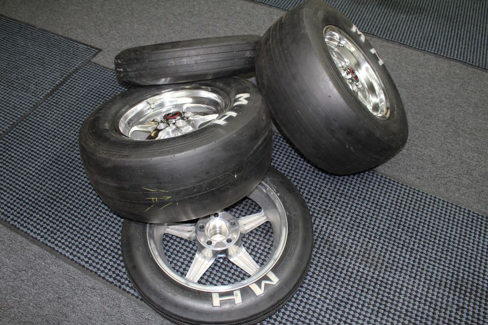 M&H slick tires on polished and brushed five-spoke aluminum drag wheels on a checkered floor