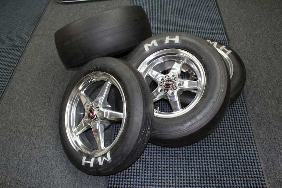 Three M&H drag slicks on polished five-spoke aluminum wheels on a checkered floor