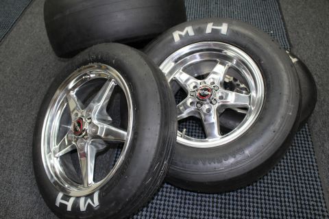 2003 Ford Crown Victoria - M&H drag slick tires on polished five-spoke aluminum wheels with red center-cap emblems grouped on a checkered shop floor.