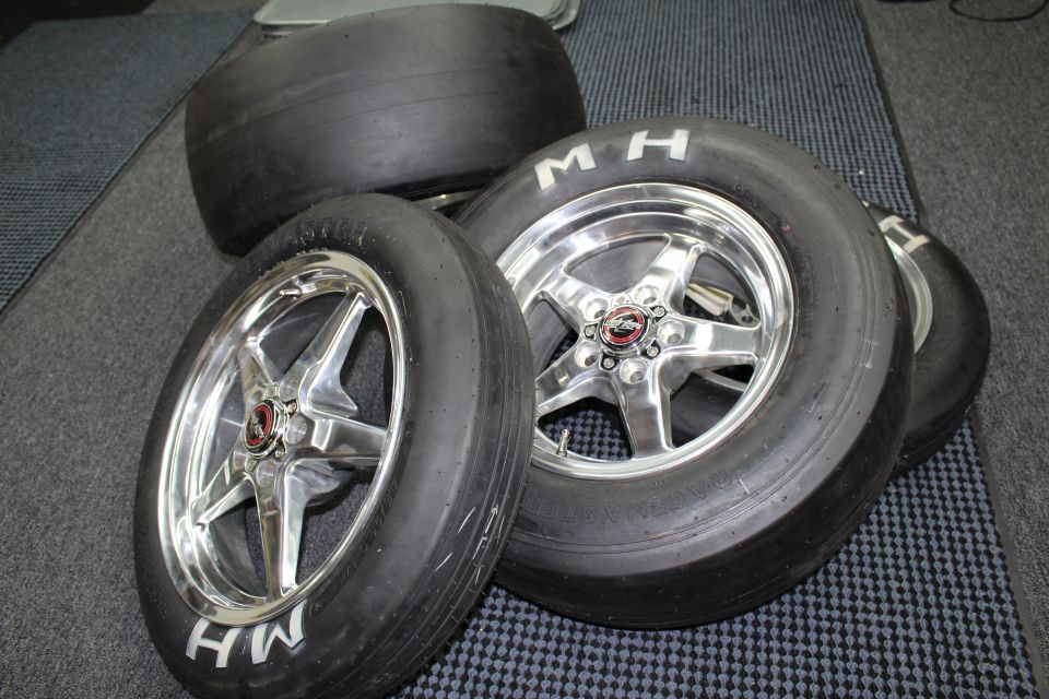 M&H drag slicks on polished five-spoke wheels with star-pattern faces on a checkered floor