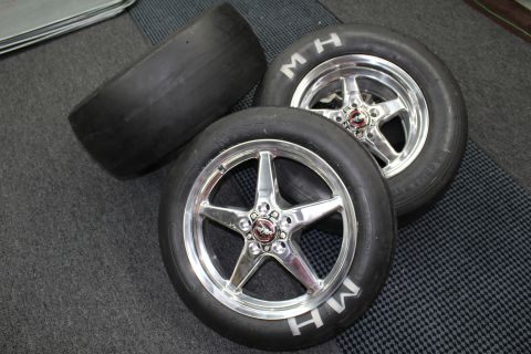 2003 Ford Crown Victoria - Two M&H drag slicks on polished five-spoke aluminum wheels with a bare slick lying behind on a gray checkered shop floor.