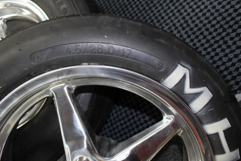 2003 Ford Crown Victoria - Close-up of a slick tire sidewall stamped 4.5/26.0-17 next to a polished five-spoke wheel showing M&H lettering.