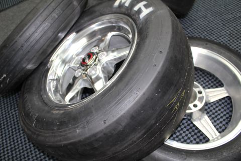 2003 Ford Crown Victoria - Close-up of slick tires on polished and brushed five-spoke aluminum drag wheels grouped on a gray checkered shop floor.