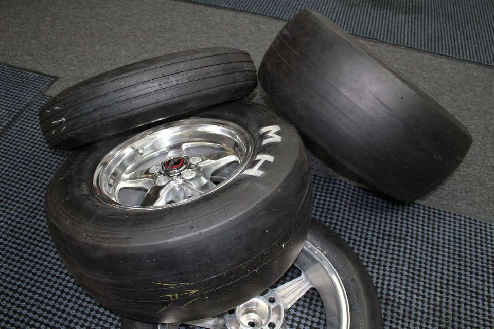 Stack of drag slick tires on polished wheels with MH lettering